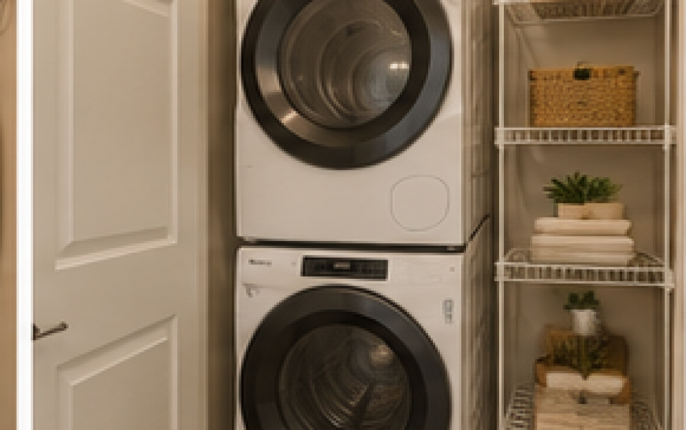 In-home stacked washer and dryer in the A3.4 apartment at Ironwood at Waldorf Station with additional shelving and storage